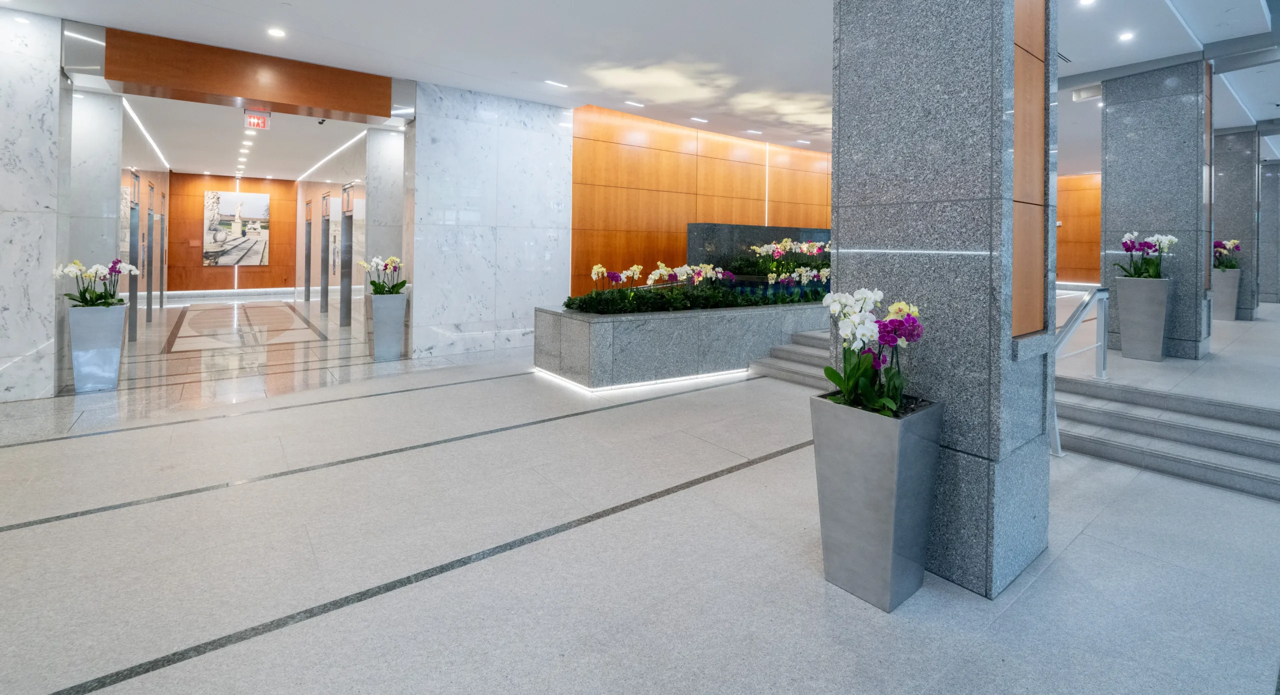 building lobby with flower planters in front of columns and an elevator bank in the background