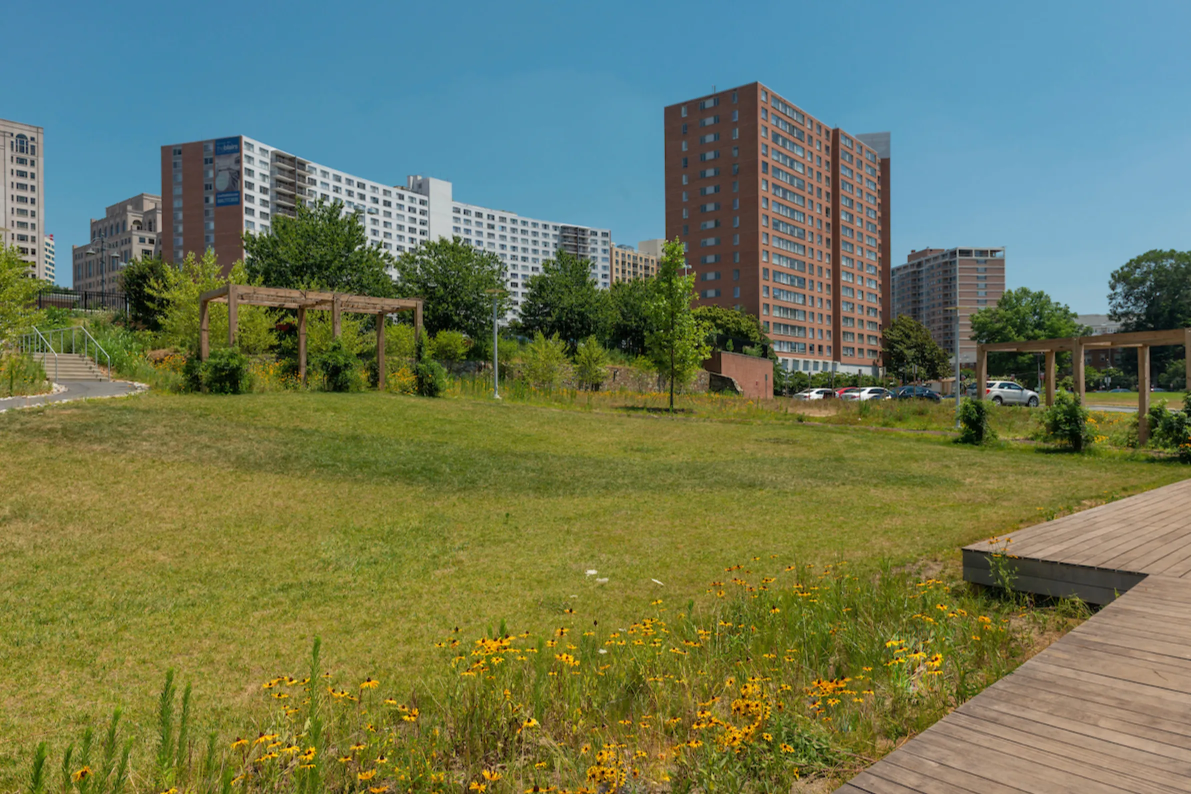 green space with flowers and pergolas and high rise apartment buildings in the background