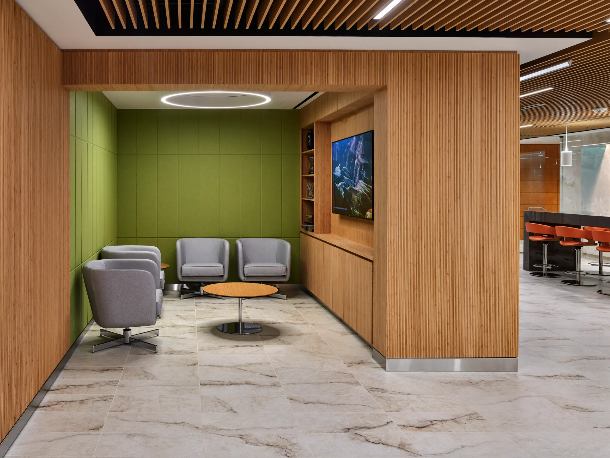 four gray armchairs, a table, and flat screen TV in an apartment building lounge