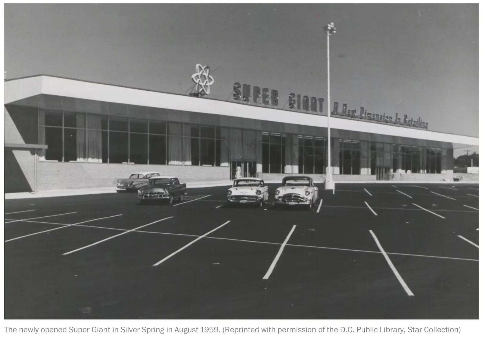 black and white image from the 1950's of a super market with a few cars in the parking lot