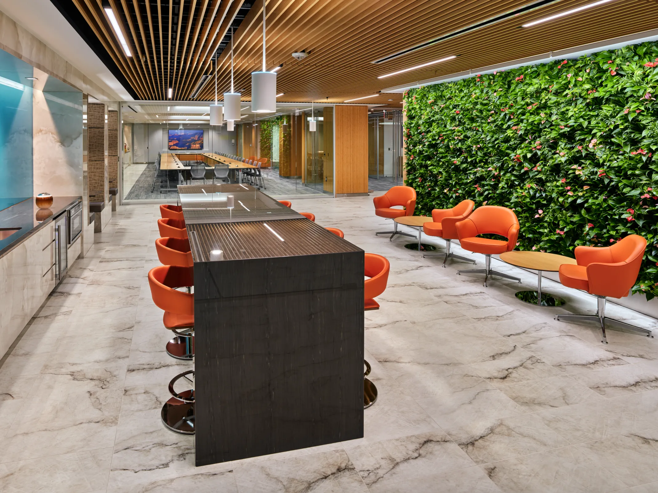 table and chairs and orange chairs and coffee tables in front of a green wall