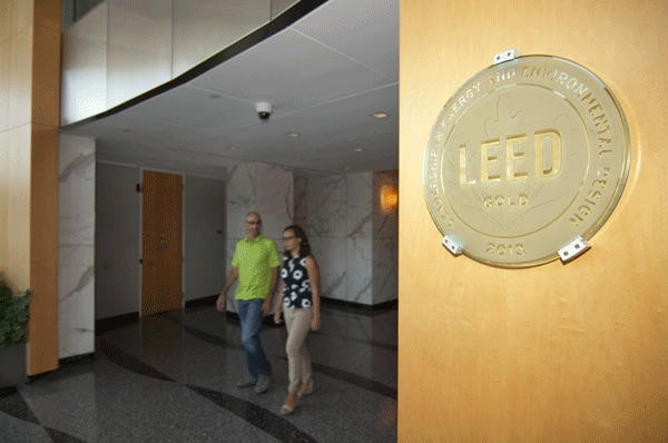 LEED Gold plaque on a wall with two people walking in the background